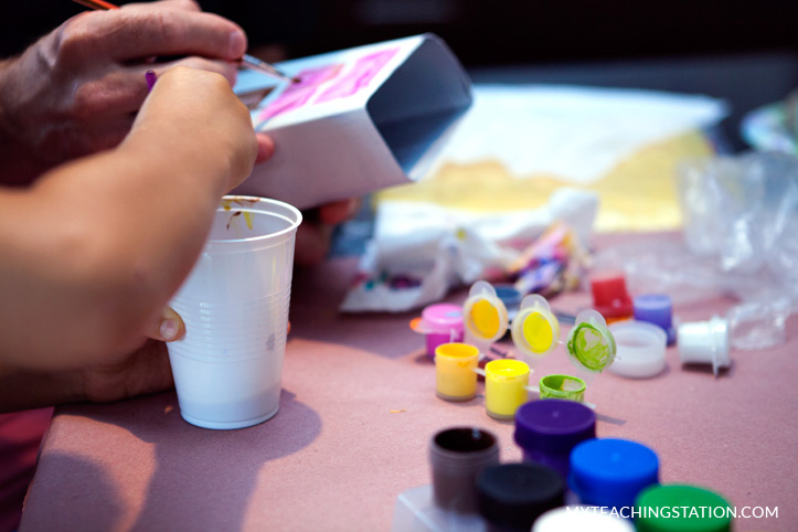 Child drawing windows in milk carton to make a building